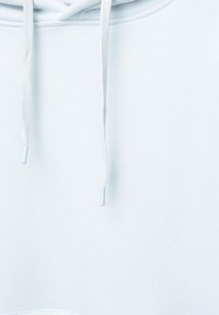 Gros plan d'un tissu de sweat à capuche blanc montrant l'encolure et deux cordons suspendus avec des embouts en plastique.