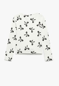 Langsleeve top in witte stof met een zwart strikpatroon. Beschikt over een ronde halslijn en ribbelstructuur op de mouwen en de zoom.