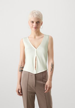 Top sans manches côtelé vert clair avec un décolleté en V profond et une fermeture à boutons, présentant une découpe en trou de serrure à l'avant.