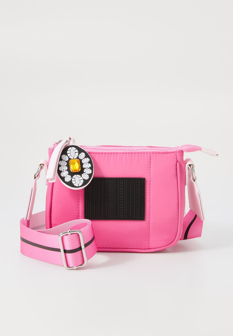 Rosa nylon crossbody-väska med en quiltad design, en svart texturerad panel, en dekorativ brosch och en avtagbar rem med ett svart stripe.
