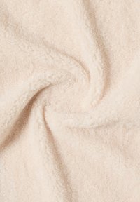 Lys beige fleece stof med en blød, tekstureret overflade, der fremstår fluffy og tætsiddende arrangeret i et svungent mønster.
