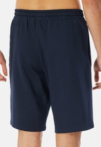 Marineblauwe katoenen shorts met een elastische tailleband, zijzakken en een relaxte pasvorm, waarbij een gladde textuur en eenvoudig ontwerp worden getoond.