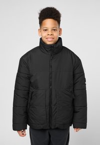 Giacca a vento nera con colletto alto, chiusura con zip e tasche frontali. Presenta un design trapuntato e orlo e polsini regolabili.