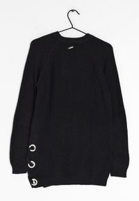 Pull noir côtelé avec un col rond, des manches raglan et trois œillets argentés avec des cordons sur le côté gauche. Suspendu à un crochet.