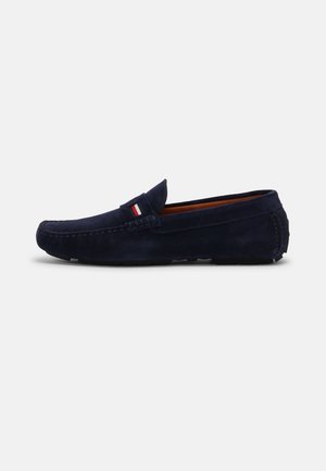 Navyblauwe suède loafer met mocassinnaad, zachte zool en klein rood-wit-blauw stoffen detail bovenop.