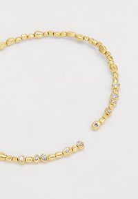 Collier en perles dorées avec des formes alternant entre lisses et texturées, comportant plusieurs cristaux en forme de goutte d'eau incrustés parmi les perles.