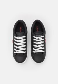Black synthetic leather sneakers with white laces, round toe, and textured detailing. Red Levi's tab logo on the side and inside.