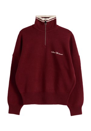 Marjapuuronvärinen neulepusero, jossa valkoiset raidat pystykauluksessa, edessä vetoketju, resorit hihansuissa ja helmassa sekä pieni valkoinen kirjallinen logo rinnassa.