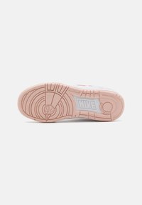Nike tenisica s potplatom od svijetloružičaste gume, s kružnim uzorkom i oznakom brenda u sivoj boji. Tekstura za bolje prianjanje i vuču.
