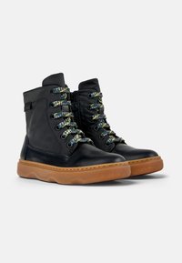 Stivali alla caviglia in pelle nera con lacci intrecciati colorati, zip laterale e suola in gomma texturizzata con motivo a onde.