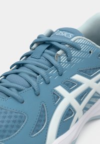 Μπλε αθλητικό παπούτσι τρεξίματος Asics με λευκό λογότυπο, λεπτομερές διχτυωτό ύφασμα και συνθετικά επικάλυψη, με σφιχτά δεμένα κορδόνια σε λευκό φόντο.