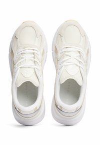 Witte en beige sport sneakers met bovenkant van mesh en leer, ronde neus, gevoerde kraag en dikke rubberen zool. Veters en logo op de tong.