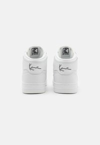 Hvite lær midttopp sneakers med en glatt finish, med et logo på hælen og en håndskrevet signaturdetalj.