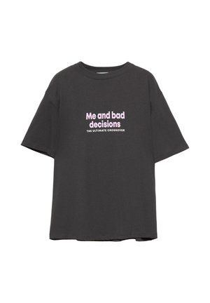 T-shirt nera in cotone a vestibilità ampia con testo rosa che recita "Io e cattive decisioni" e "IL CROSSOVER ULTIMO". Maniche corte, collo rotondo.