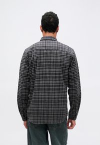 Črna in siva karirasta srajca dolgi rokavi s ovratnikom, z gumbi spredaj in nastavljivimi manšetami. Mehka tkanina z udobnim krojem.