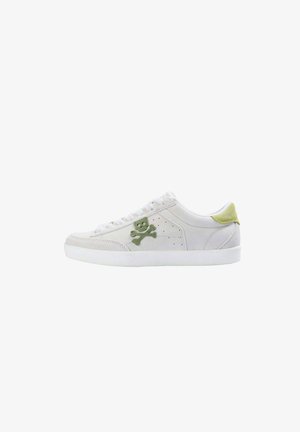 Basket en suède blanche avec une broderie de tête de mort et os croisés verte sur le côté, des accents texturés, et un onglet de talon contrastant en vert clair.