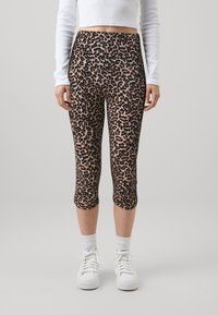 Leggingse do leopardovog uzorka, od rastezljivog materijala, sa visokim strukom i dužinom do gležnjeva, kombinirani s bijelim tenisicama.