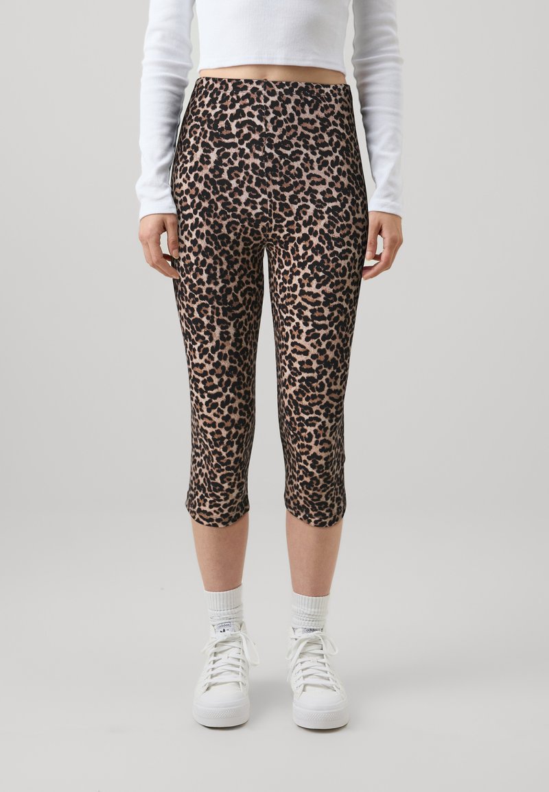 Leggingse do leopardovog uzorka, od rastezljivog materijala, sa visokim strukom i dužinom do gležnjeva, kombinirani s bijelim tenisicama.