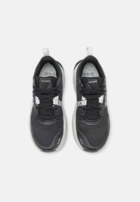 Scarpe sportive nere con tomaia in mesh, dettagli testurizzati e suola bianca. Le caratteristiche includono lacci, logo e un tassello sul tallone.