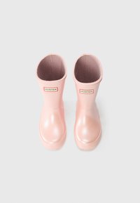 Bottes de pluie en caoutchouc roses avec une finition brillante, à bout rond et à tige courte. Présente une étiquette de marque à l'avant. Semelles en caoutchouc texturé.