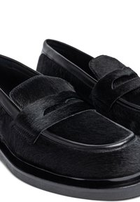 Zwarte loafers van textuurvacht met een gladde zwarte leren band en een afgeronde neusontwerp. Voorzien van een subtiele stikselafwerking.