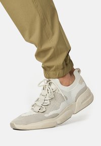 Letvægts net sneakers i creme og beige, med en tekstureret overdel, snørebåndslukning og en polstret sål med et afrundet tådesign.