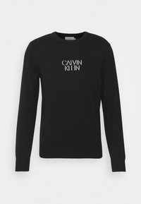 Schwarzer Sweatshirt aus Baumwolle, mit langen Ärmeln und Rundhalsausschnitt. Auf der Brust ist das weiße "CALVIN KLEIN"-Logo aufgedruckt.