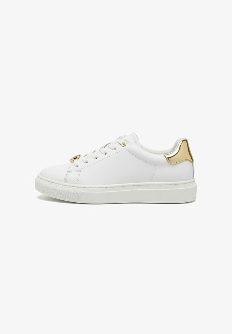 Witte lage sneaker met gouden veterogen en een gouden metalen hielstuk, voorzien van een dikke witte rubberen zool.
