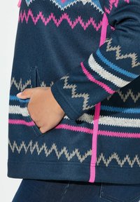 Navyblauer Strickpullover mit geometrischen Mustern in Pink, Grau und Blau. Verfügt über eine Fronttasche und Akzentdetails in lebhaftem Pink.