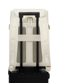 Cremfarbener Rucksack mit strukturiertem Rücken, verstellbaren Trägern und einem schwarzen teleskopischen Griff, der zum Anbringen an Gepäck konzipiert ist.