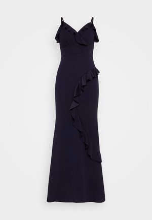 Navy blue evening dress featuring spaghetti straps, ruffle accents at the neckline and a side ruffle detail, made from a smooth fabric.