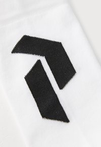 Witte sok met een opvallend zwart zigzag logo ontwerp. Het materiaal ziet er zacht uit met een gestructureerde afwerking.