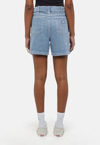Shorts de ganga azul claro com cintura alta, apresentando dois bolsos traseiros e um patch com o logótipo cosido. Comprimento até à meia coxa, com detalhes de bainha desfiada.