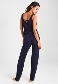 Marineblaues zweiteiliges Lounge-Set mit ärmellosem Oberteil und Rückenträgern sowie locker sitzenden Hosen, aus weichem Material für besonderen Komfort.