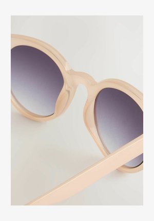 Occhiali da sole oversize con montatura traslucida rosa chiaro, lenti grigie sfumate e finitura liscia e lucida. Templi larghi e piatti.