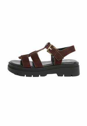 Pruun seemisnahast sandaal kolme esiosa paelaga, kuldse pandlaga, musta polsterdatud tallaga ja jämeda, soonilise platvormiga.