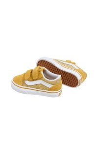 Zapatillas de ante amarillas con acentos de purpurina, franjas laterales blancas y tiras de velcro. Presentan una suela de goma texturizada con un patrón de panal.
