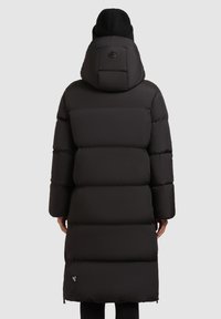 Sort pufferjakke med hætte, med en quiltet design og elastiske manchetter. Inkluderer et logo på ryggen og en længere silhuet.