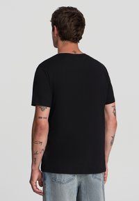 T-shirt nera a maniche corte con colletto tondo. Realizzata in cotone morbido, presenta una vestibilità regolare senza logo o motivi visibili.