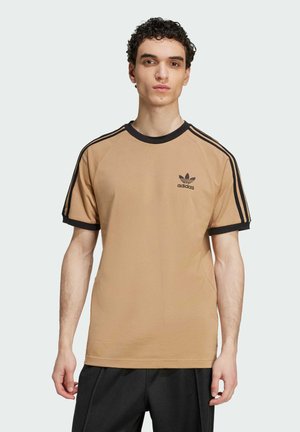 Camiseta de algodón marrón con cuello de canalé negro, mangas cortas y rayas verticales negras. Presenta un pequeño logo negro de Adidas en el pecho.