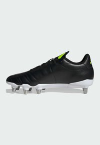 Zwarte voetbalschoenen met een slank ontwerp, gestructureerd leren bovenwerk, contrasterende witte zool en metalen noppen voor grip; heldergroene accenten.