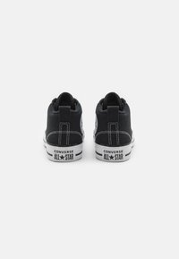 Juodos drobės aukštakulniai sportbačiai su baltais padais, su kontrastinga siūlų siuvimu ir apskritu logotipu šone. „Converse All Star“ ženklinimas.