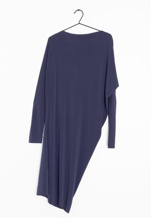 Námorně modré asymetrické šaty s dlouhým rukávem visící na černém kovovém ramínku na bílém pozadí.