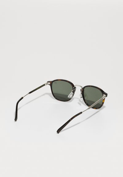 Brown tortoiseshell sunglasses with green lenses, metallic bridge and arms, and black temple tips. Distinctive, rounded shape.