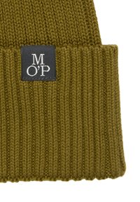 Dzianinowa czapka typu beanie w oliwkowej zieleni o prążkowanej fakturze. Na przodzie ma czarną metkę z białymi literami "M O' P" przeszytymi.