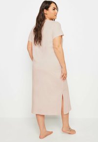 Abito midi a maniche corte, di un tenue rosa pallido, con taglio dritto e spacco laterale, realizzato in tessuto morbido, caratterizzato da un collo rotondo e una vestibilità comoda.