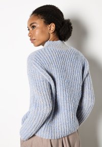 Helles Blau, geripptes Strickpullover mit hohem Kragen und abfallenden Schultern, der eine weiche Textur und eine lockere Passform bietet.