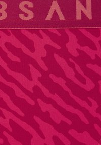 Vaaleanpunainen kangas, joka esittää hienoista tiikeriraidallista kuviota, ja siinä on kontrastina tekstuurinen vyötäröosa, johon on kirjailtu vaaleanpunaisella tekstillä.