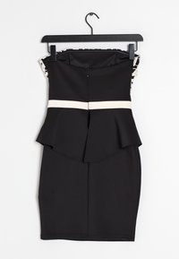 Svart peplumklänning med en åtsittande design, prydd med ett krämfärgat horisontellt accentband, texturerade axeldetaljer och en dold dragkedja.