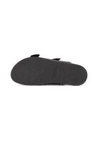 Suola di scarpa in gomma nera con un motivo testurizzato, forma arrotondata e design piatto. Presenta un leggero tacco e un branding minimale.